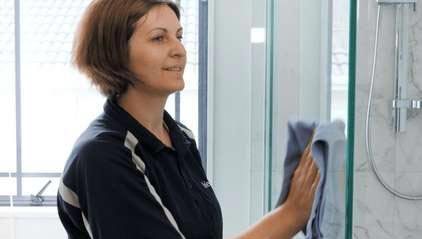 Cleaner wiping down shower glass